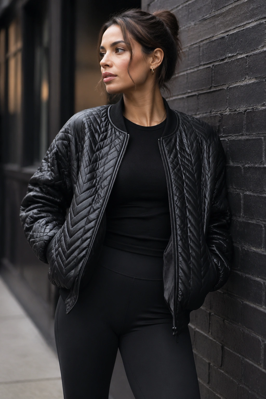 Medium close-up of a person in all-black yoga wear with a textured statement jacket outdoors