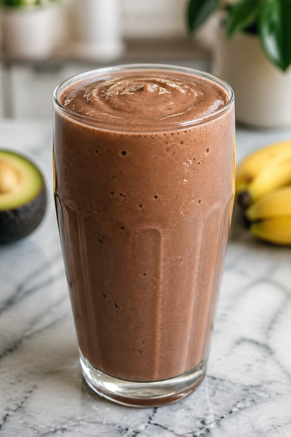 Brown-green avocado cocoa banana smoothie in a glass