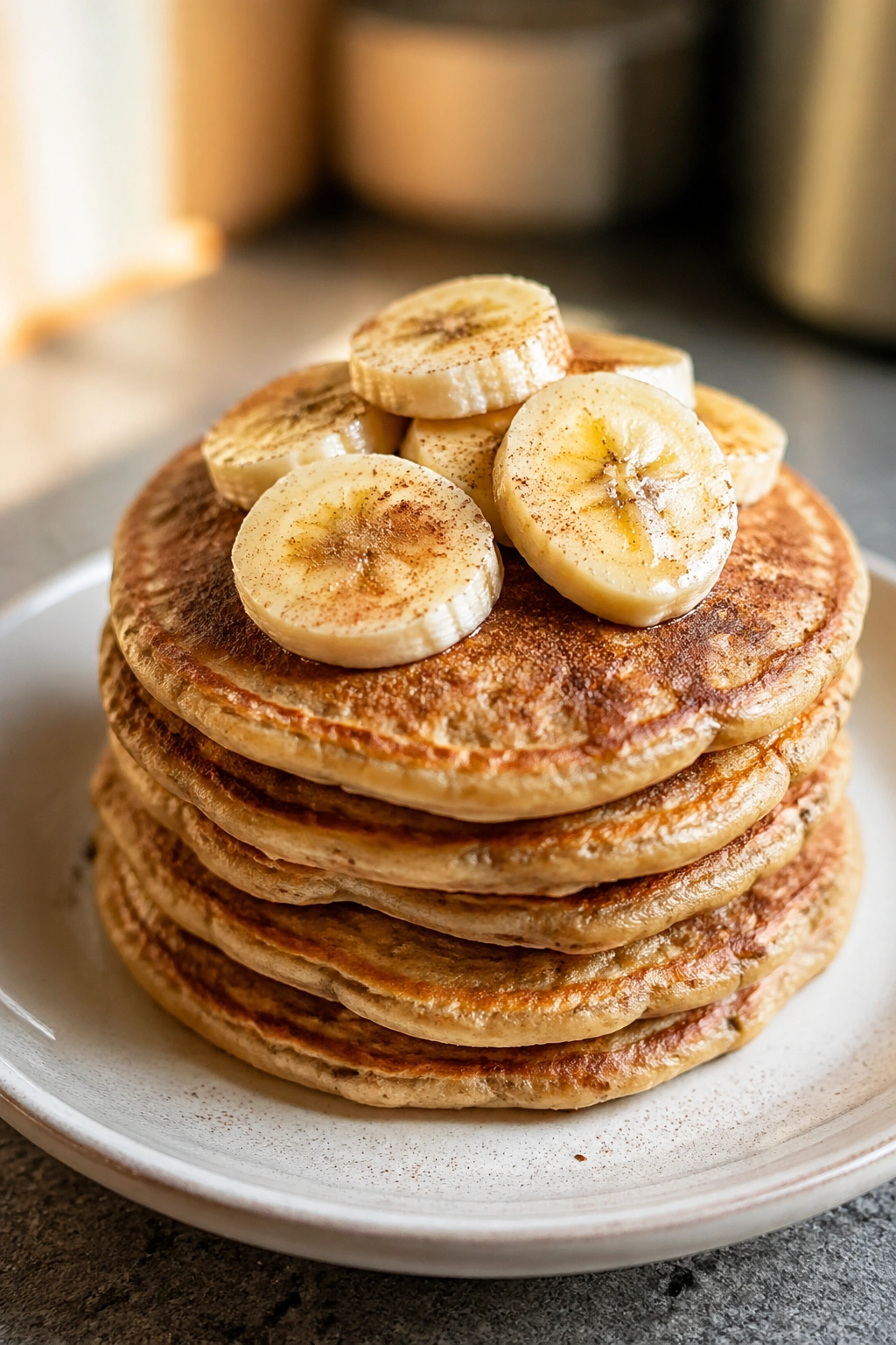 Stack of banana protein pancakes topped with banana slices