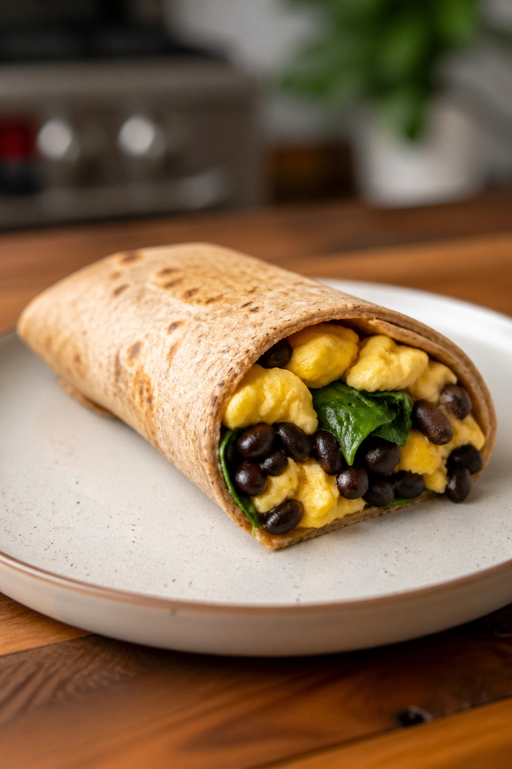 Close-up of a whole grain breakfast burrito with egg beans and spinach
