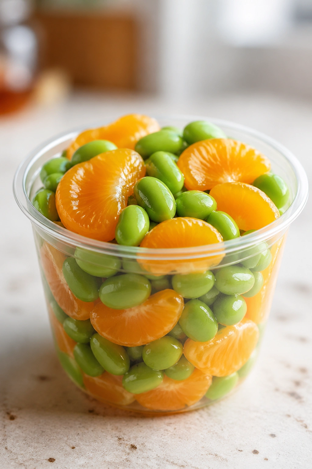 Edamame and mandarin orange cup on a kitchen counter