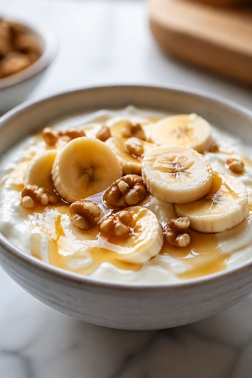 Close-up of Greek yogurt with banana and honey in a bowl on a kitchen counter