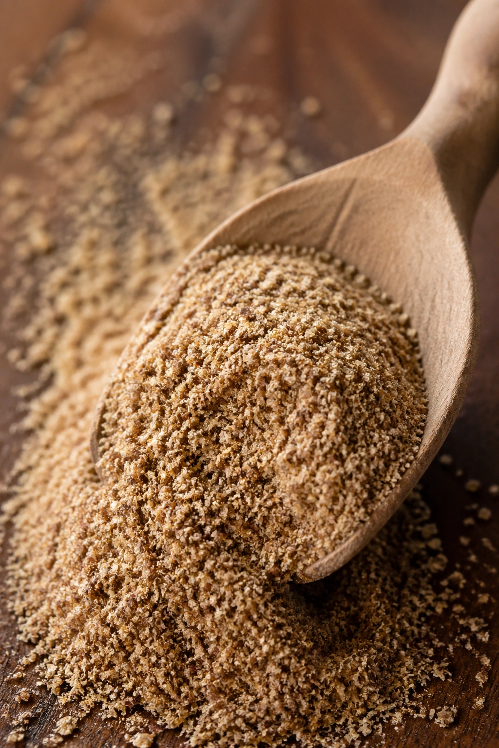 Close-up of ground flaxseed powder on a wooden surface.