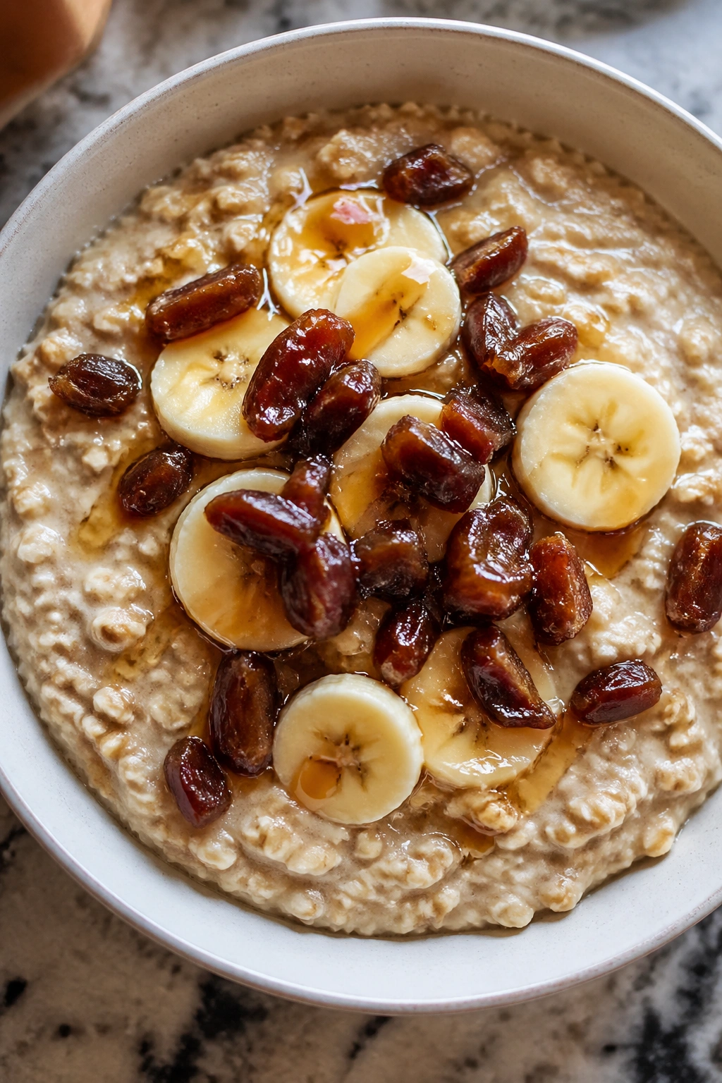 Oats with dates and banana topped with honey in a kitchen setting