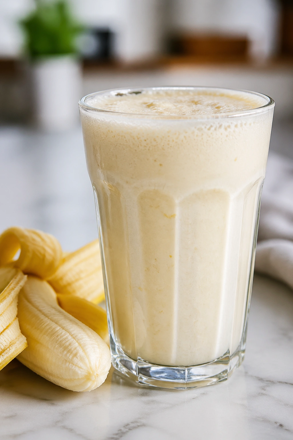 Glass of kefir banana shake with banana beside it