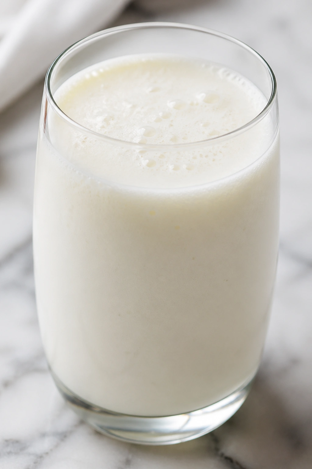 Close-up of pale kefir in a glass on a bright kitchen surface