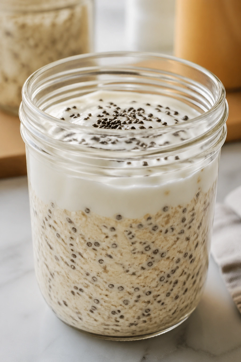Jar of overnight oats with yogurt and chia seeds on a kitchen counter
