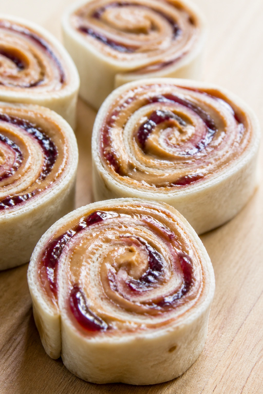 Close-up of PB&J tortilla roll-ups sliced into pinwheels on a wooden surface