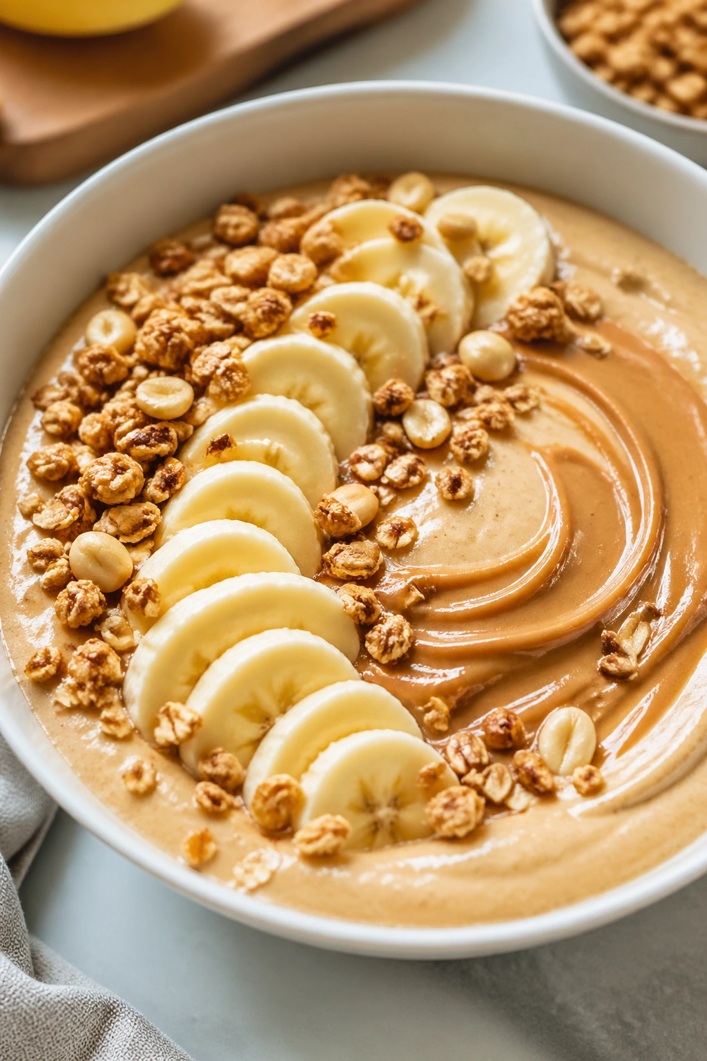 Thick peanut butter banana smoothie bowl topped with granola and banana slices