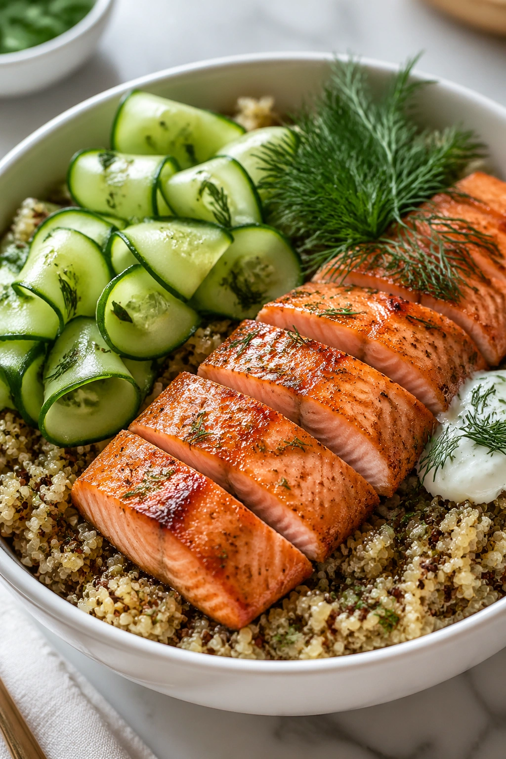 Close-up of salmon quinoa bowl with cucumber and dill