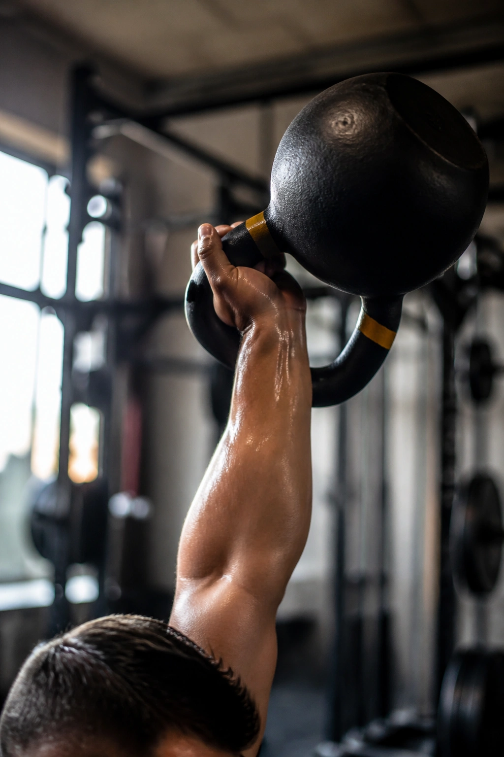 Close-up of kettlebell snatch movement on a lifter's arm in a gym