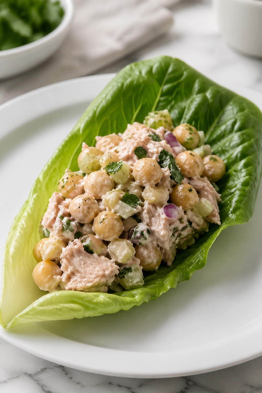 Lettuce wrap filled with tuna chickpea salad on a plate