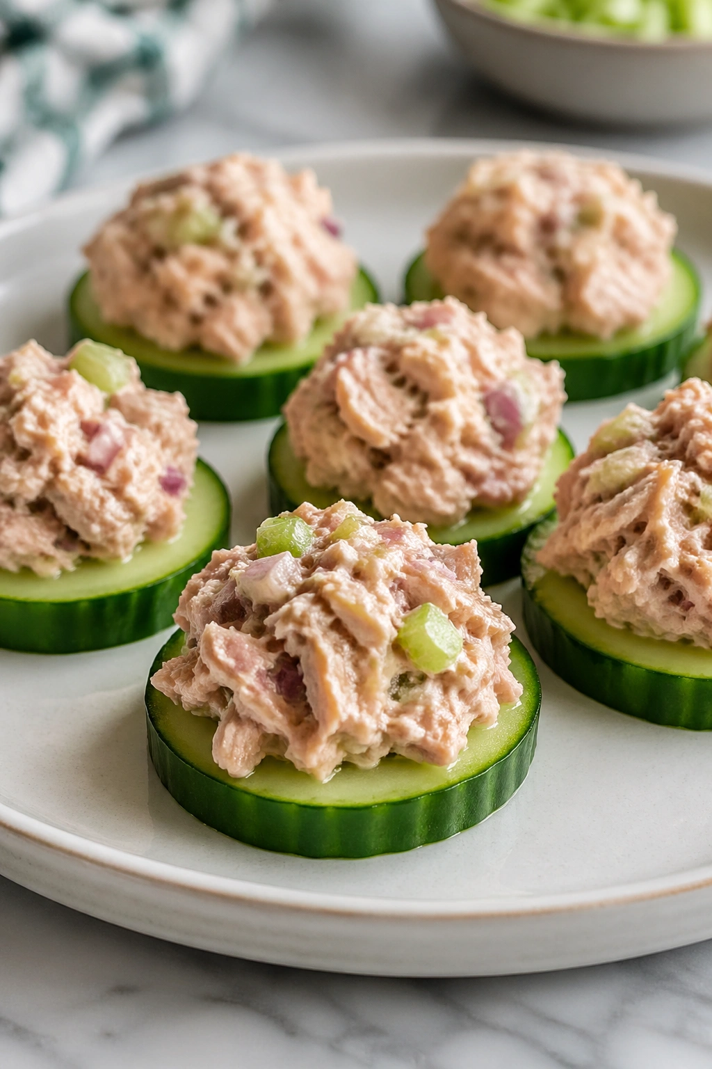 Close-up of cucumber rounds topped with tuna salad, savory post-workout snack