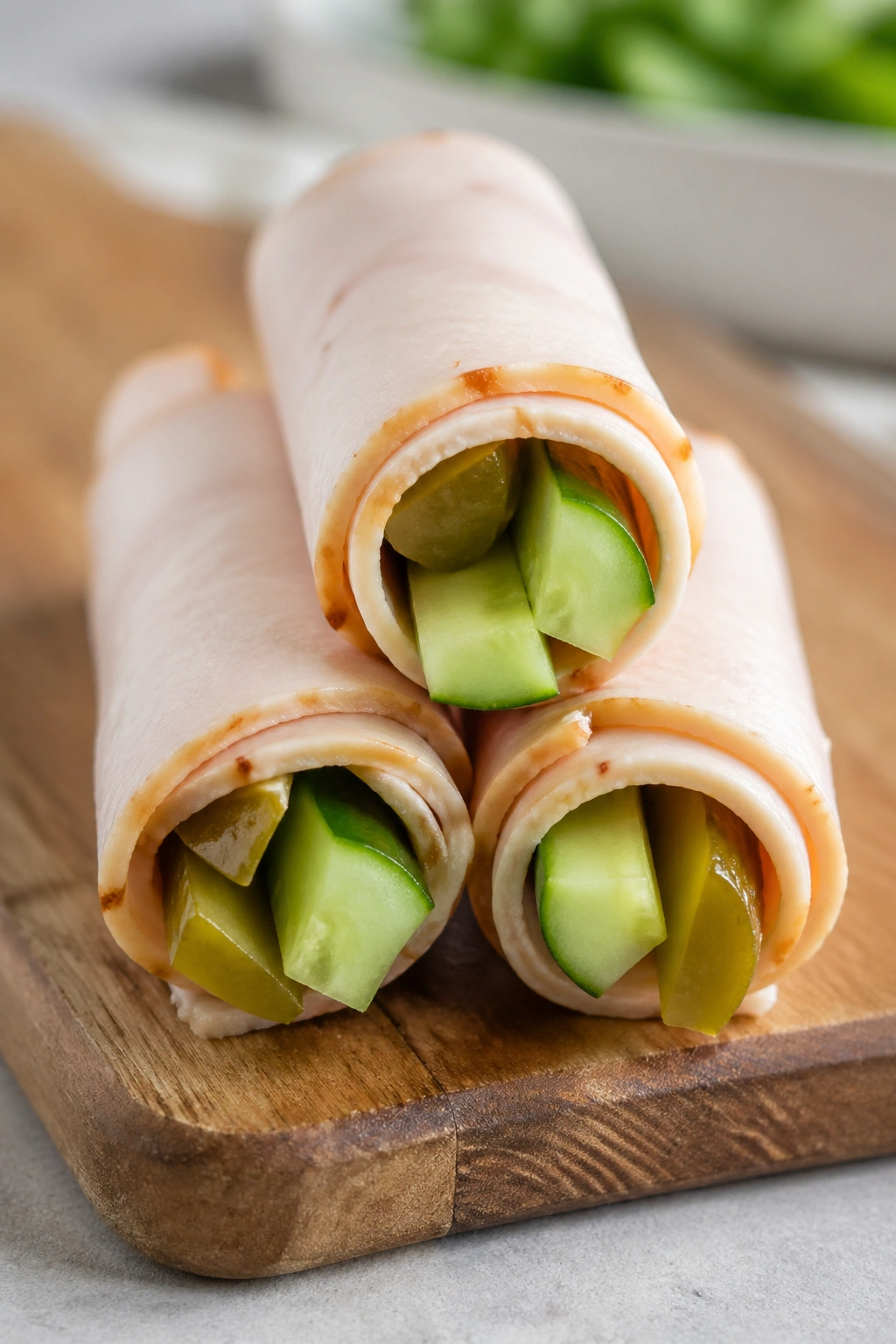 Turkey roll-ups with pickle and cucumber on a board