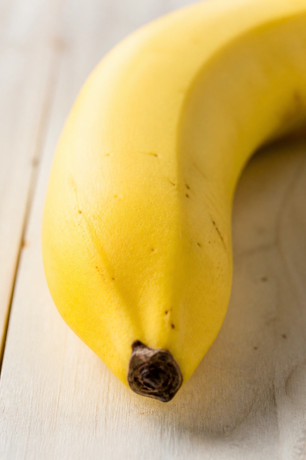 Close-up of a ripe banana on a light wooden surface