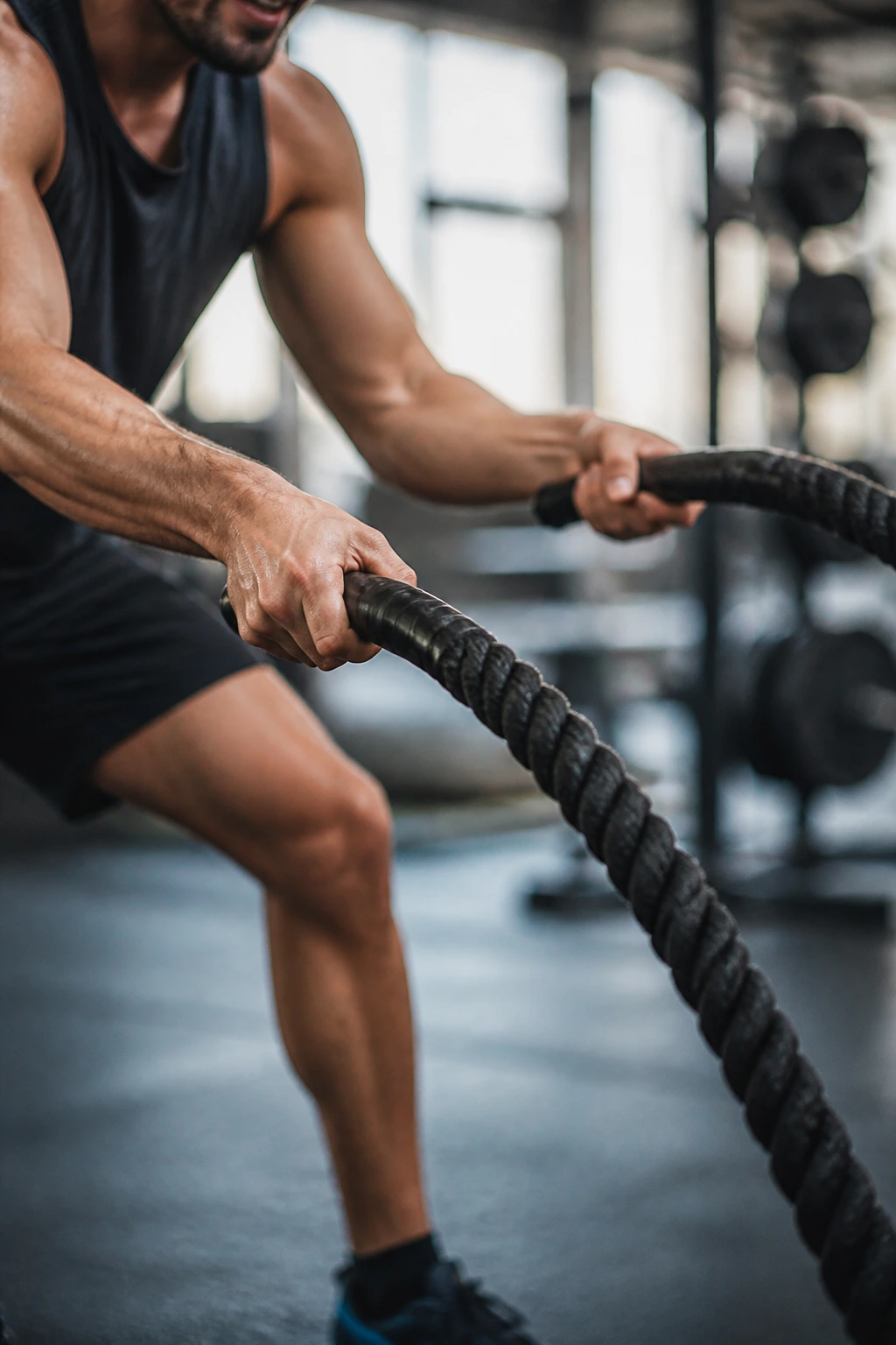 Close-up of forearms and battle rope waves during alternating bursts in a gym.