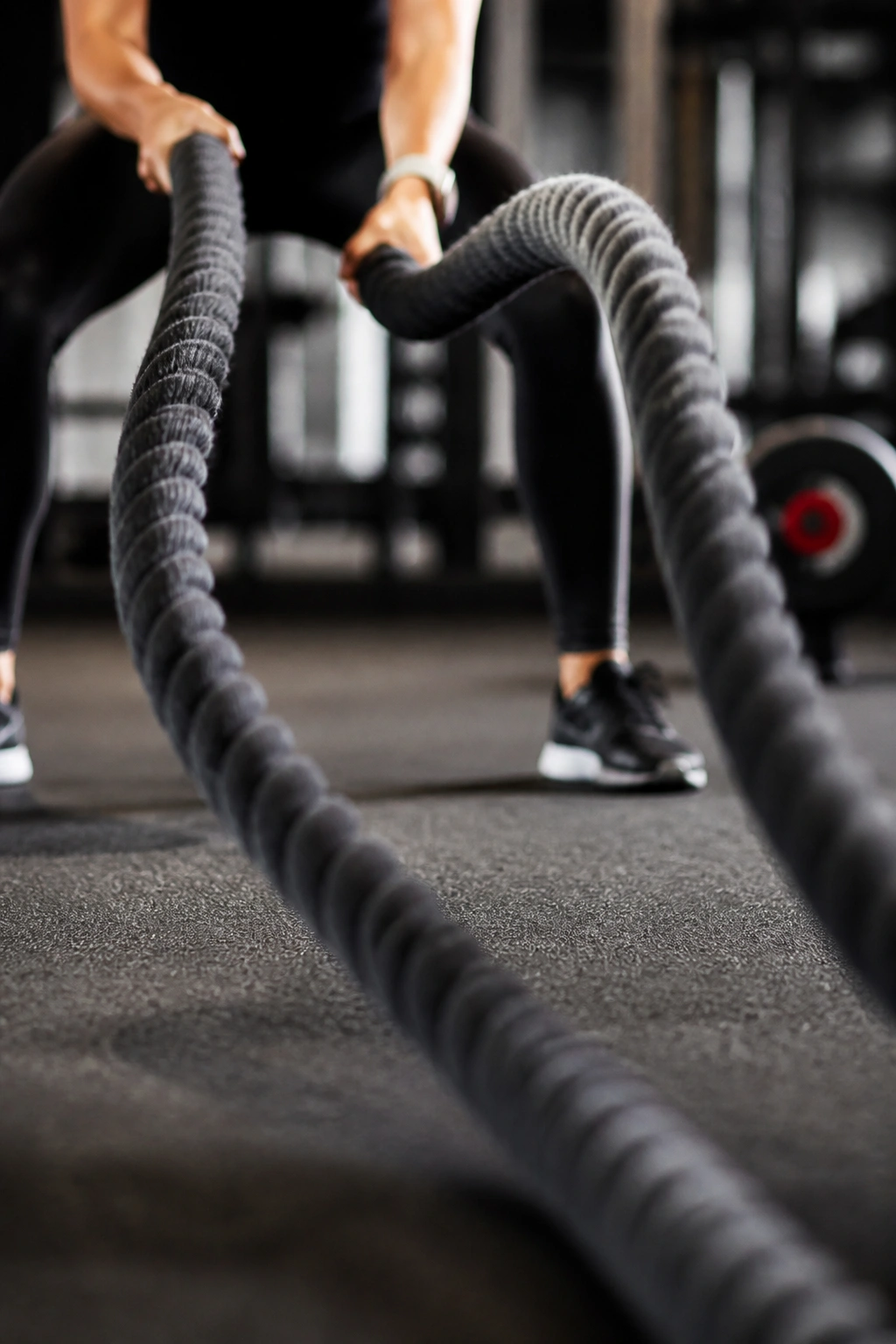 Close-up of battle ropes moving in a gym, hands gripping one rope