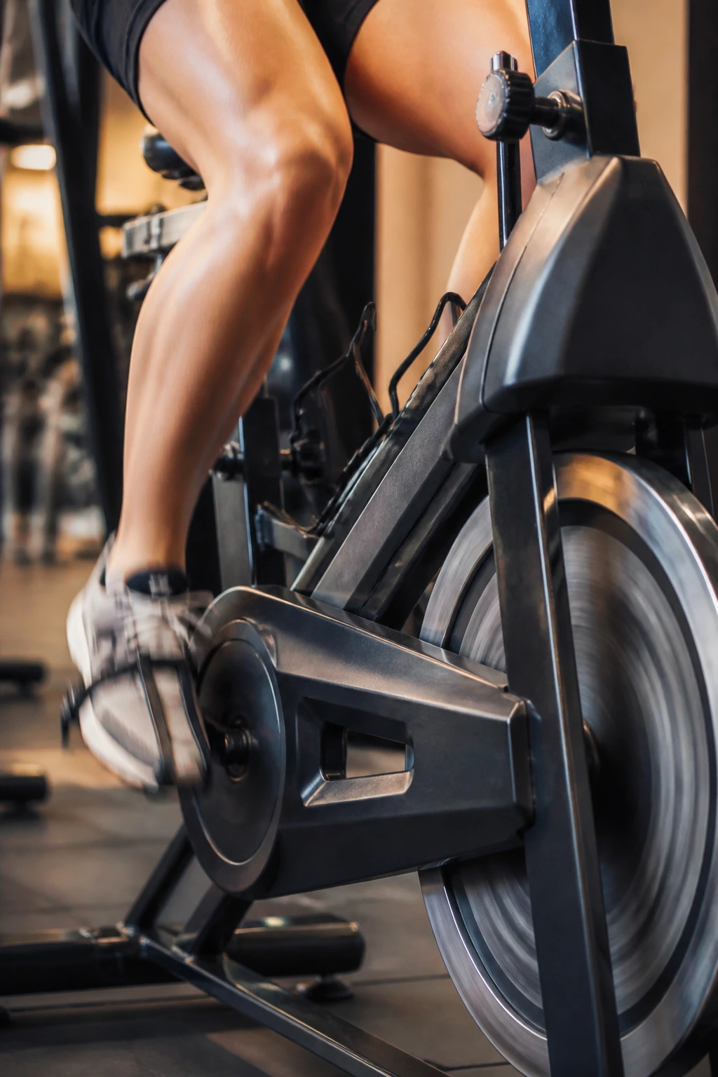 Close-up of a rider's legs pedaling on a stationary bike in a gym