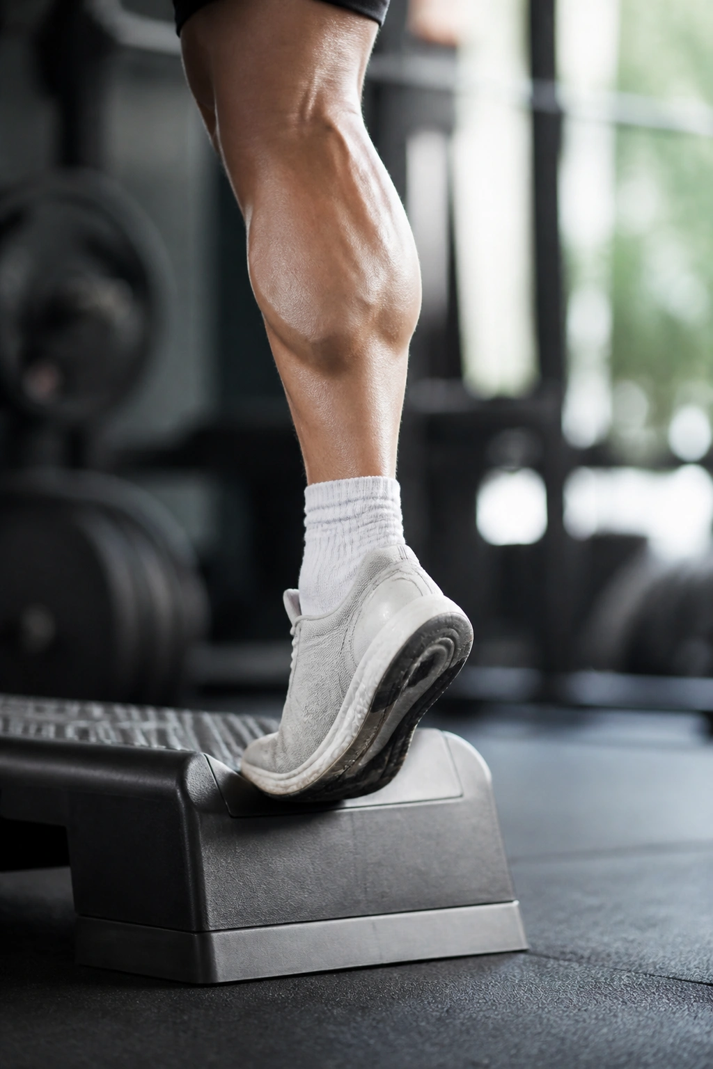 Close-up of a leg performing a single-leg calf raise on a gym step