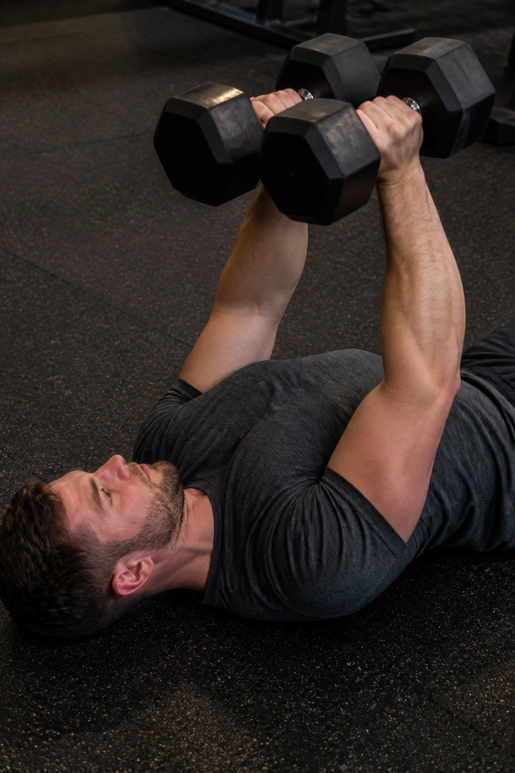 Real person performing close-grip dumbbell floor press with elbows tucked