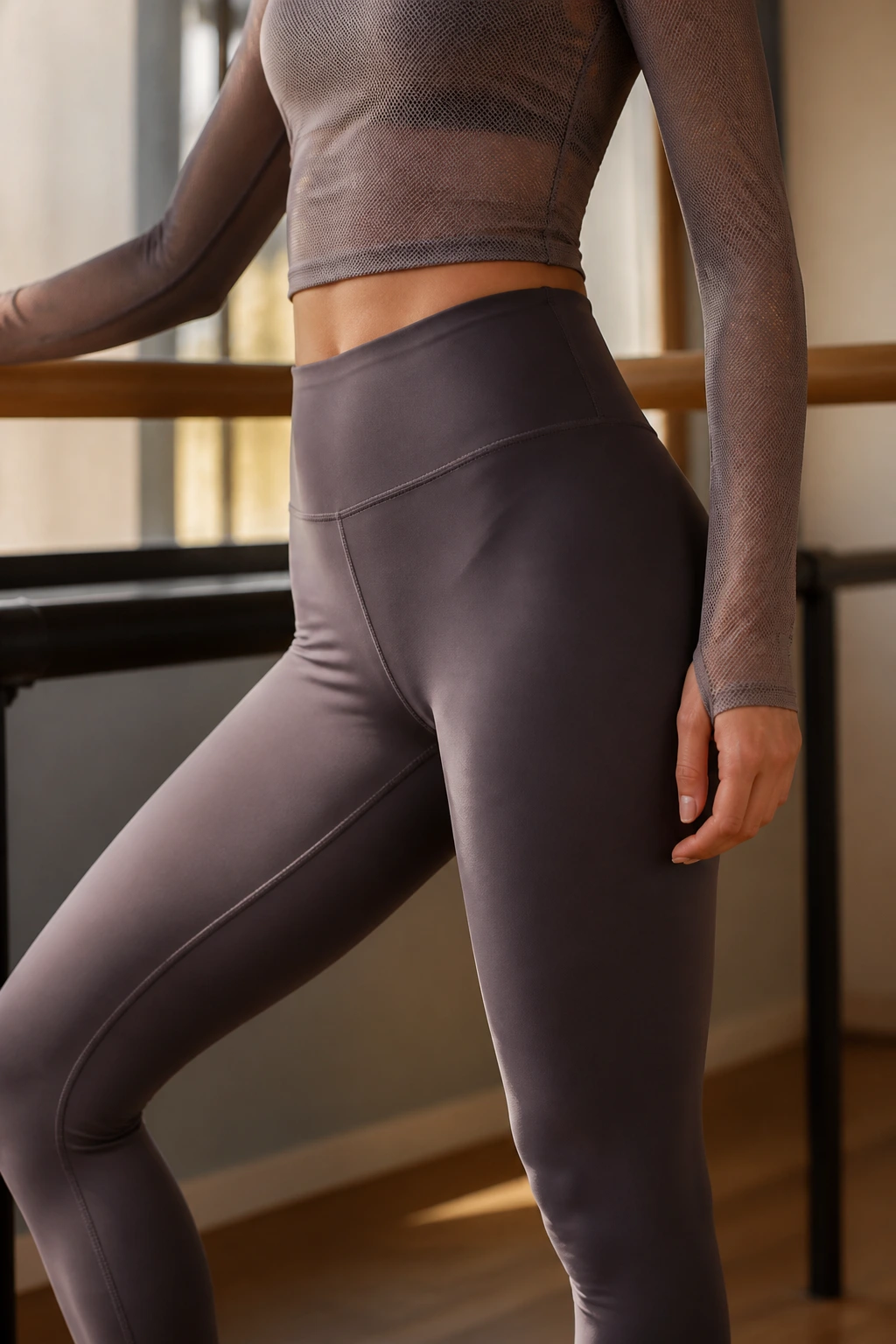 Close-up of model wearing compression tights and mesh top at barre studio