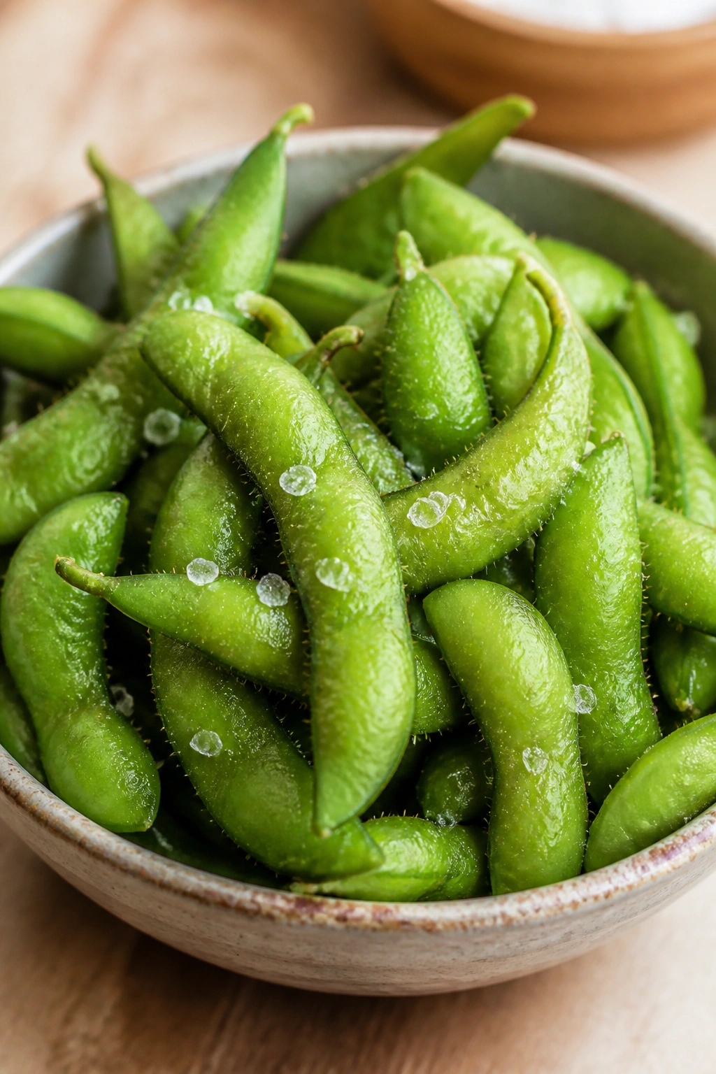 Close-up of edamame in a bowl with sea salt on a kitchen counter