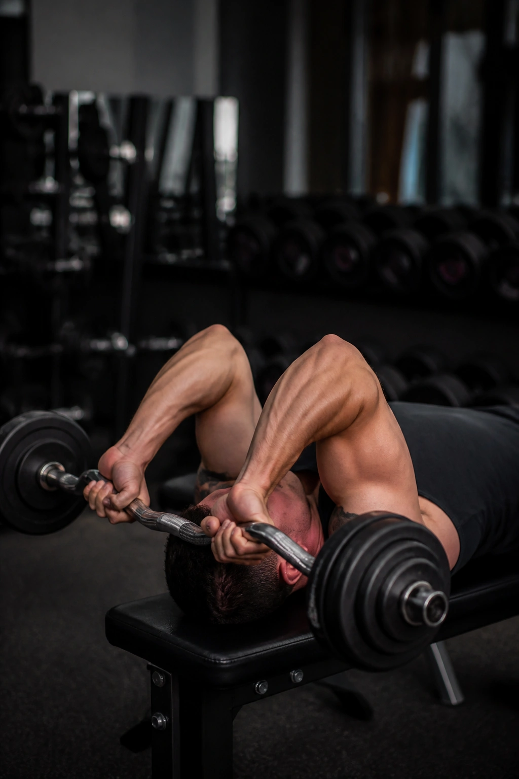 Lifter on bench performing EZ-bar skull crushers, focusing on triceps extension.