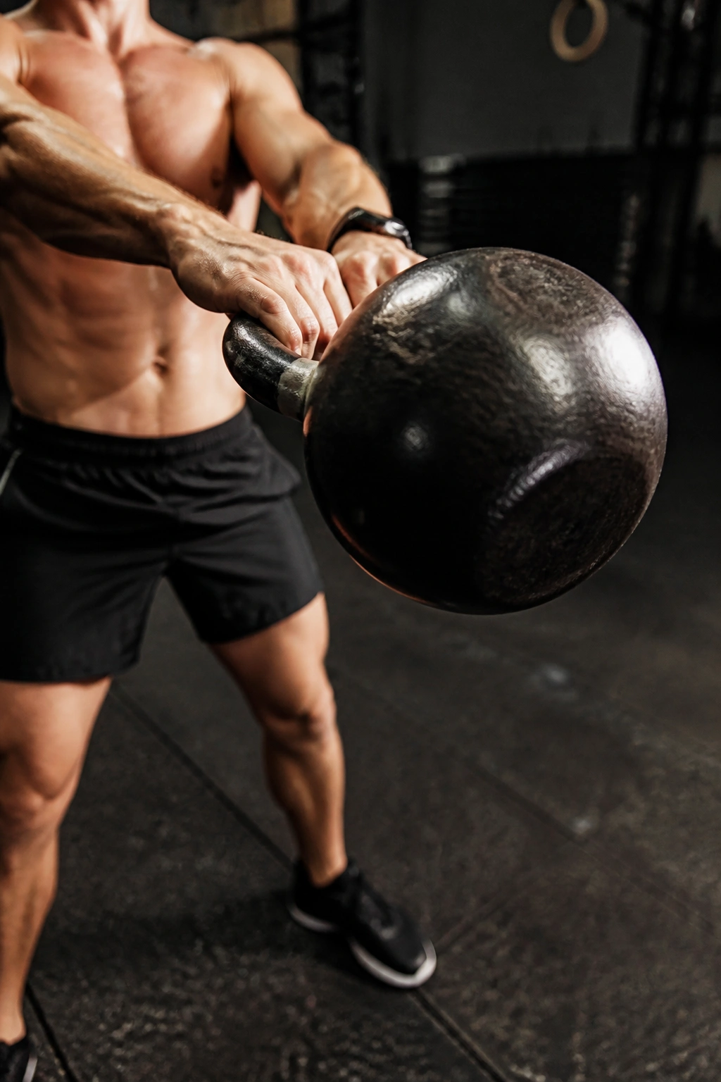 Kettlebell in mid-swing dominating the frame with a nearby forearm grip