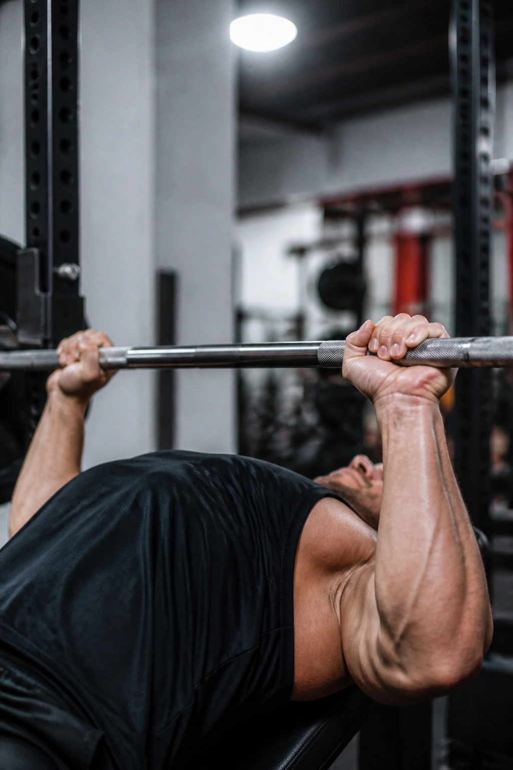 Close-up of a lifter's hands on a bar with mixed grip during paused bench press in a gym