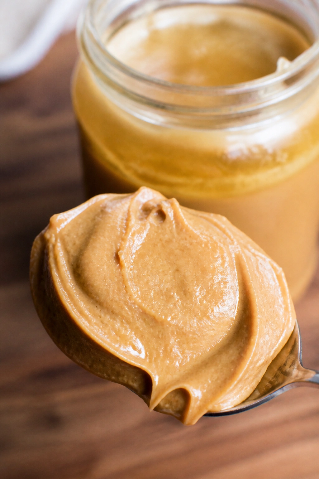 Close-up of natural peanut butter on a spoon with oil separation in a warm kitchen