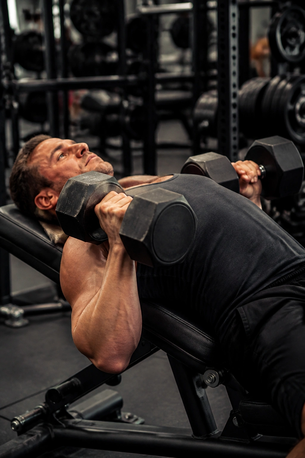 Close-up of lifter performing pause dumbbell press at chest level in a gym