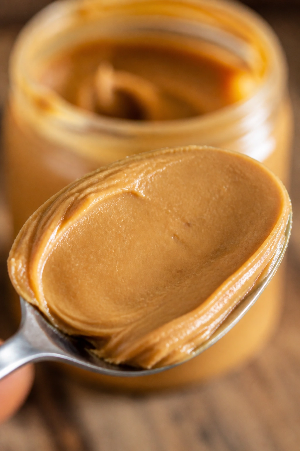 Close-up of peanut butter on a spoon with a blurred jar in the background.