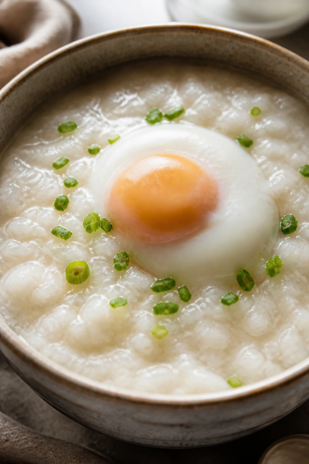 Congee with a fully cooked egg on top in a bowl
