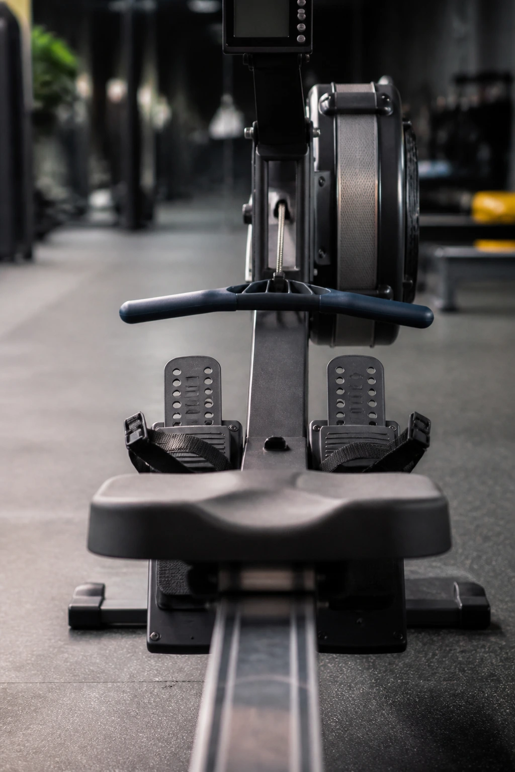 Close-up of rowing machine handle and seat dominating the gym frame