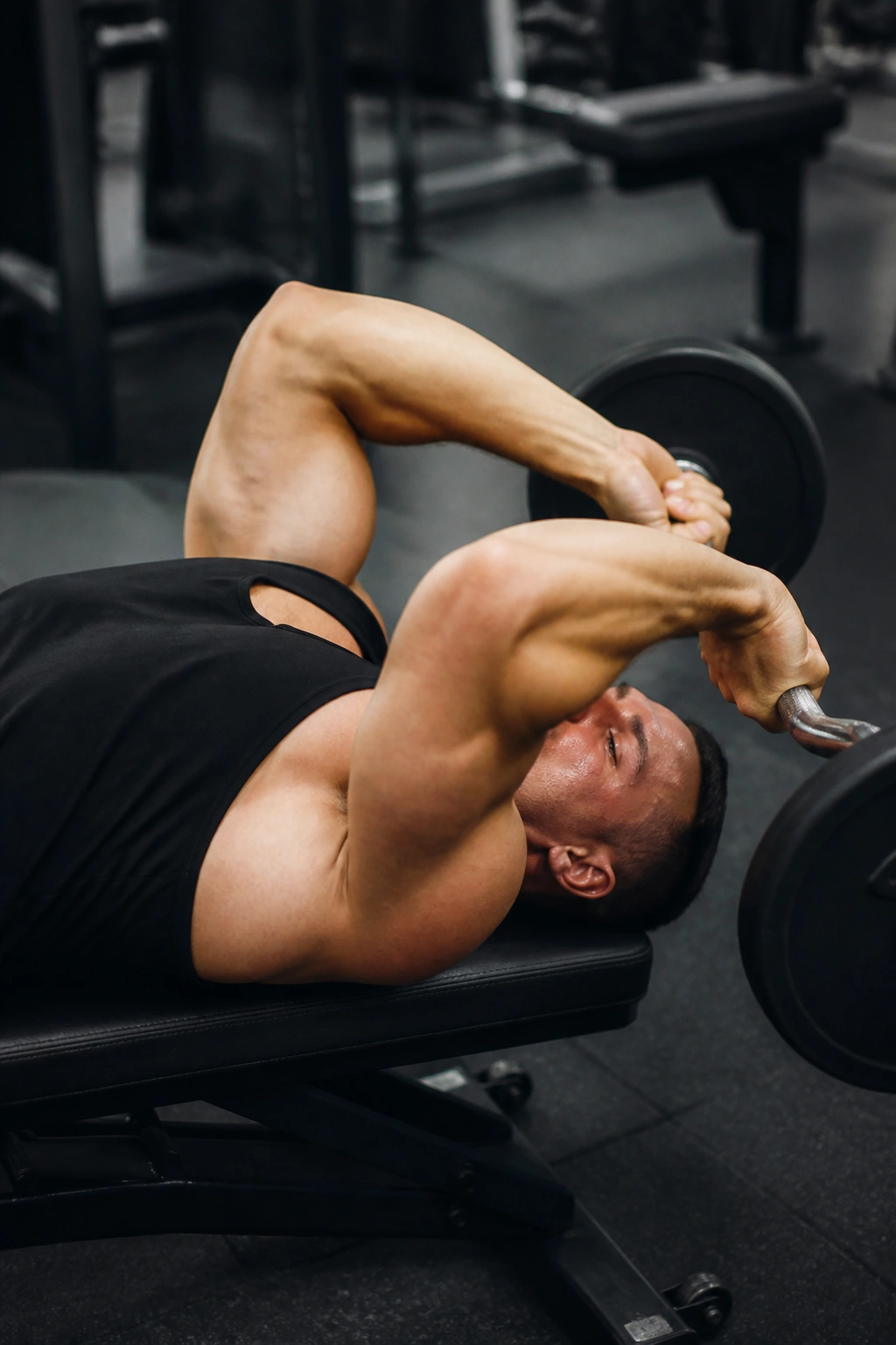 Close up of a person performing skull crushers on a bench with elbows in