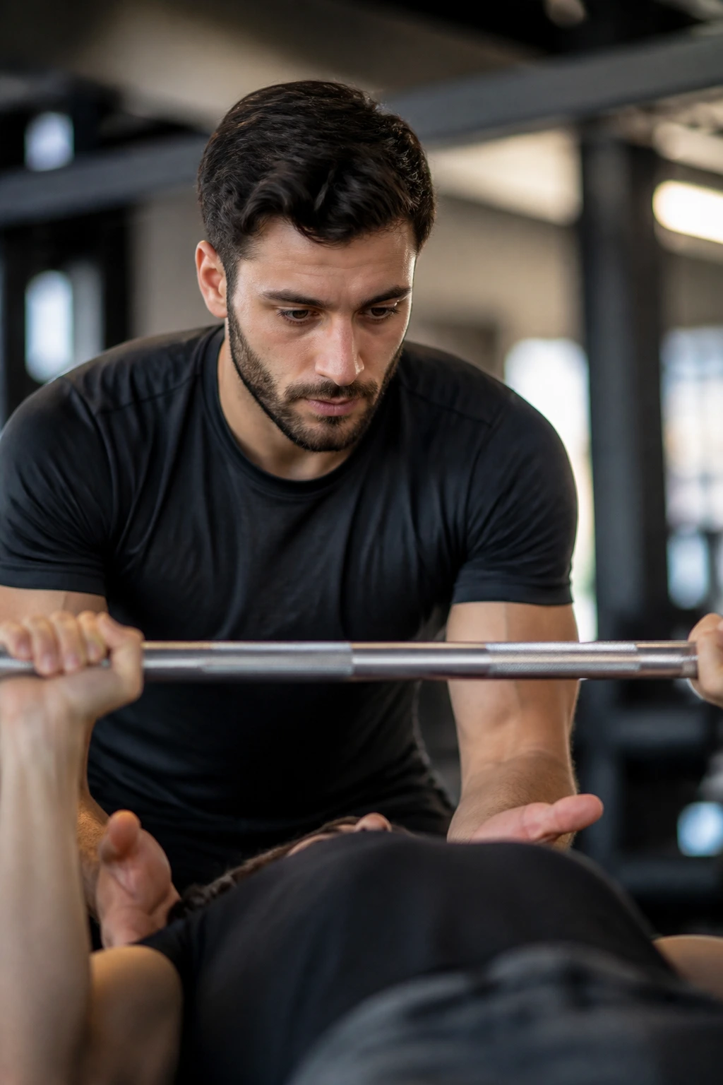 Spotter ready to assist during a bench press in a gym