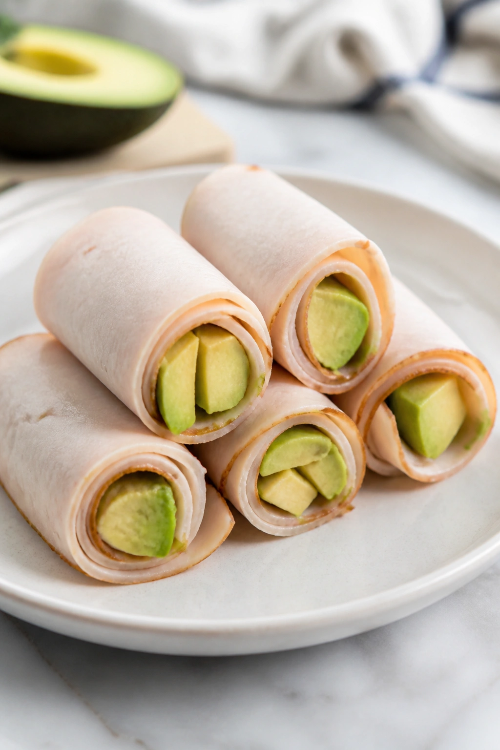Turkey roll-ups with avocado on plate in kitchen