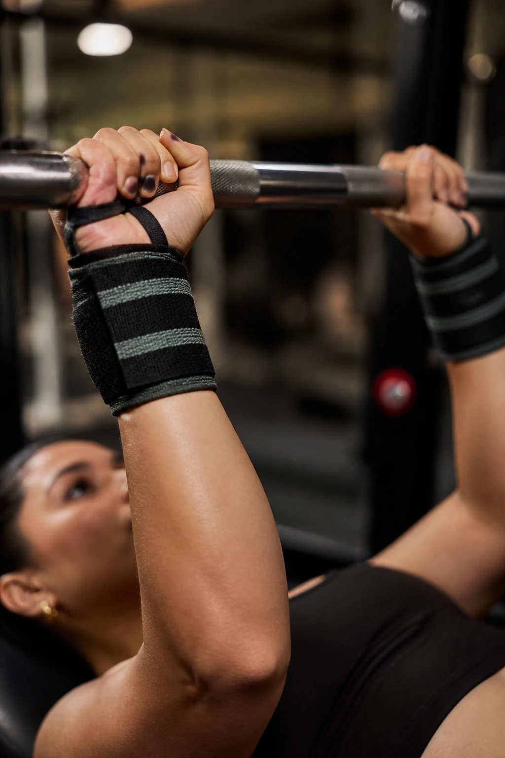 Close-up of wrists with long wrist wraps gripping a bar