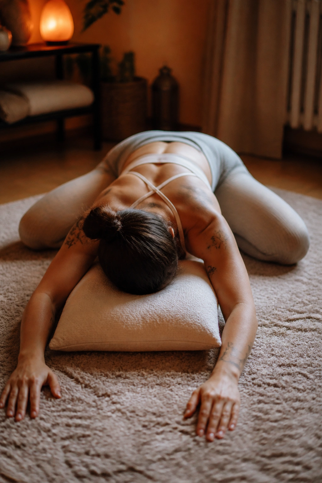 Person in wide-knee child’s pose with chest supported by pillow.