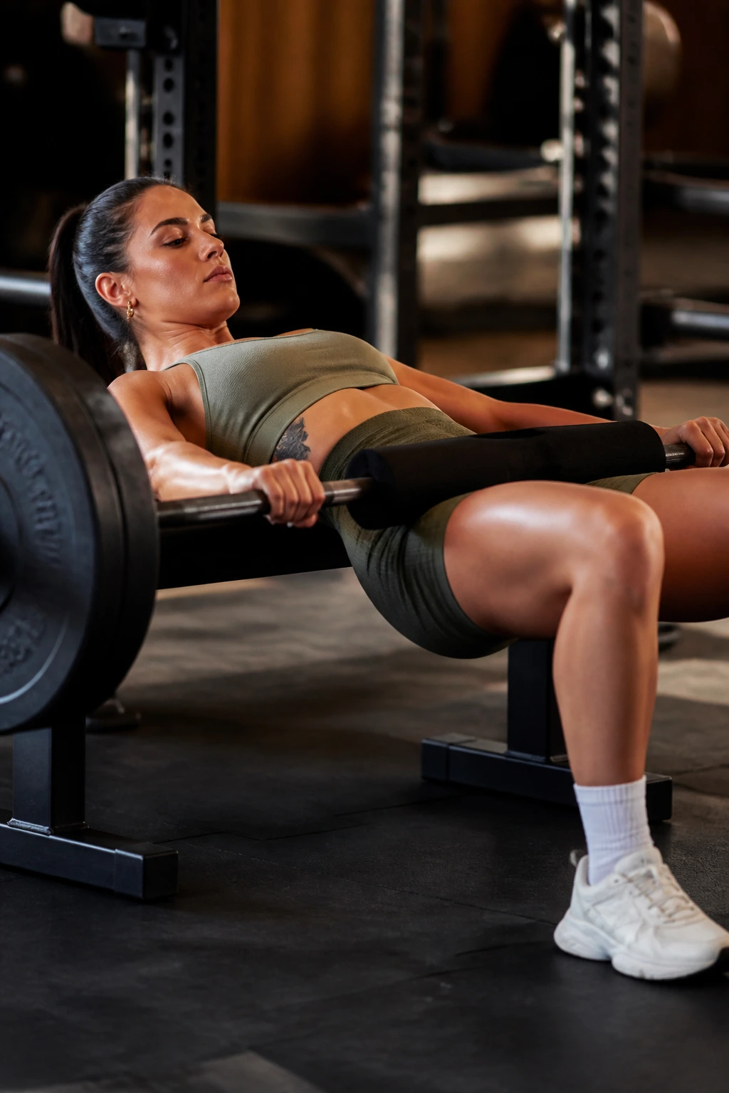 Athlete performing barbell hip thrust with paused top in gym