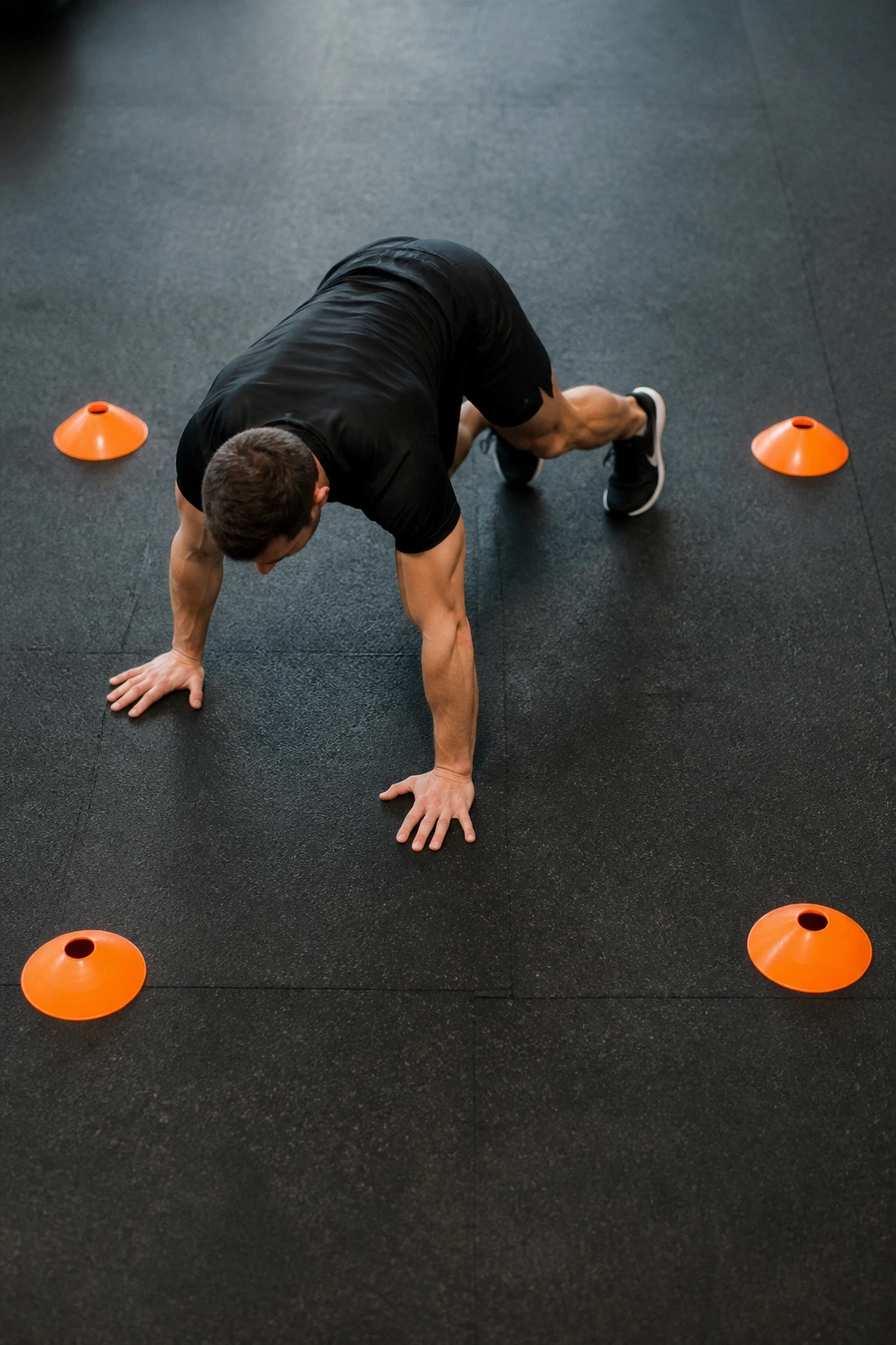 Athlete performing cone-based square crawl in a gym