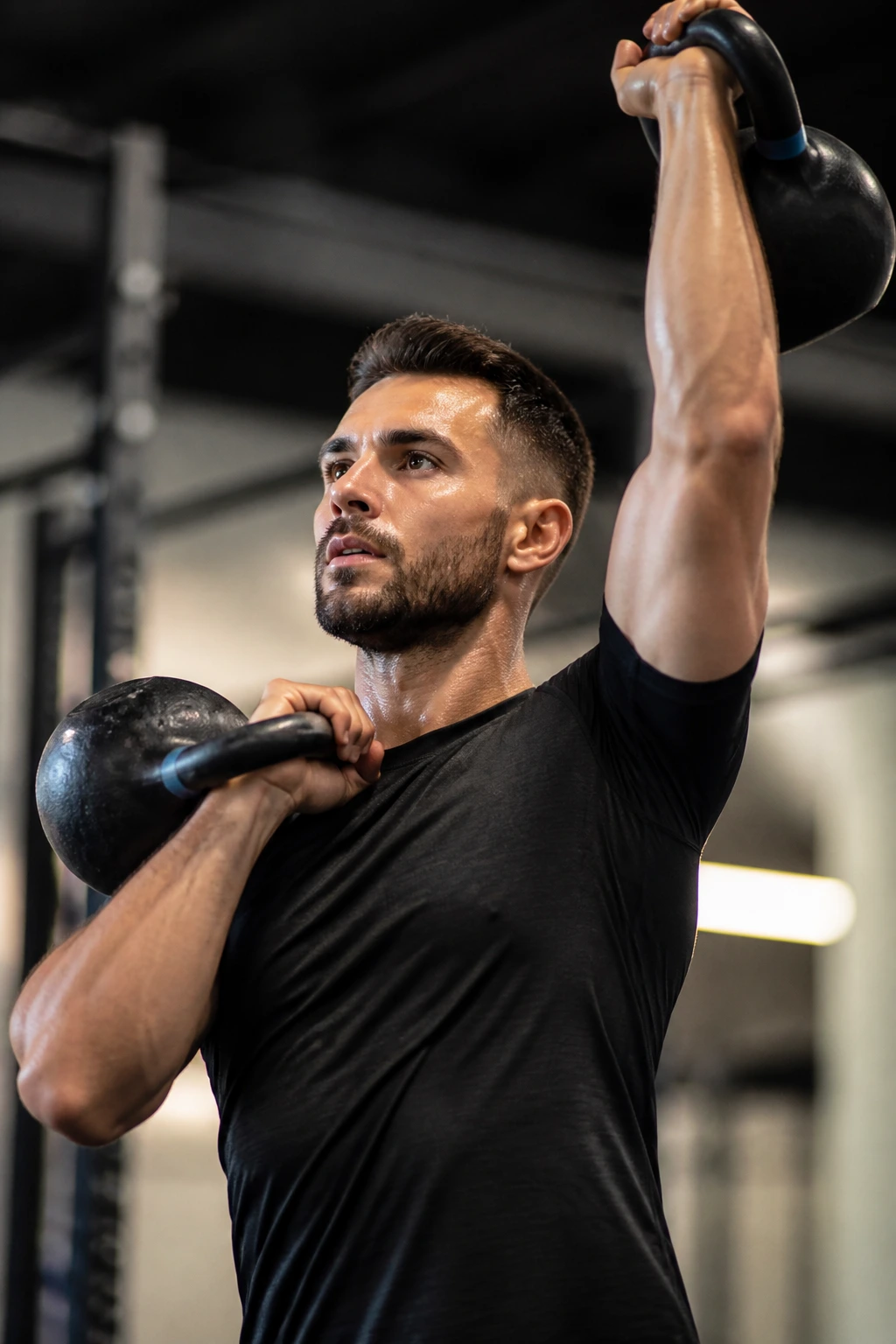 Medium close-up of a kettlebell clean-to-press in a gym setting