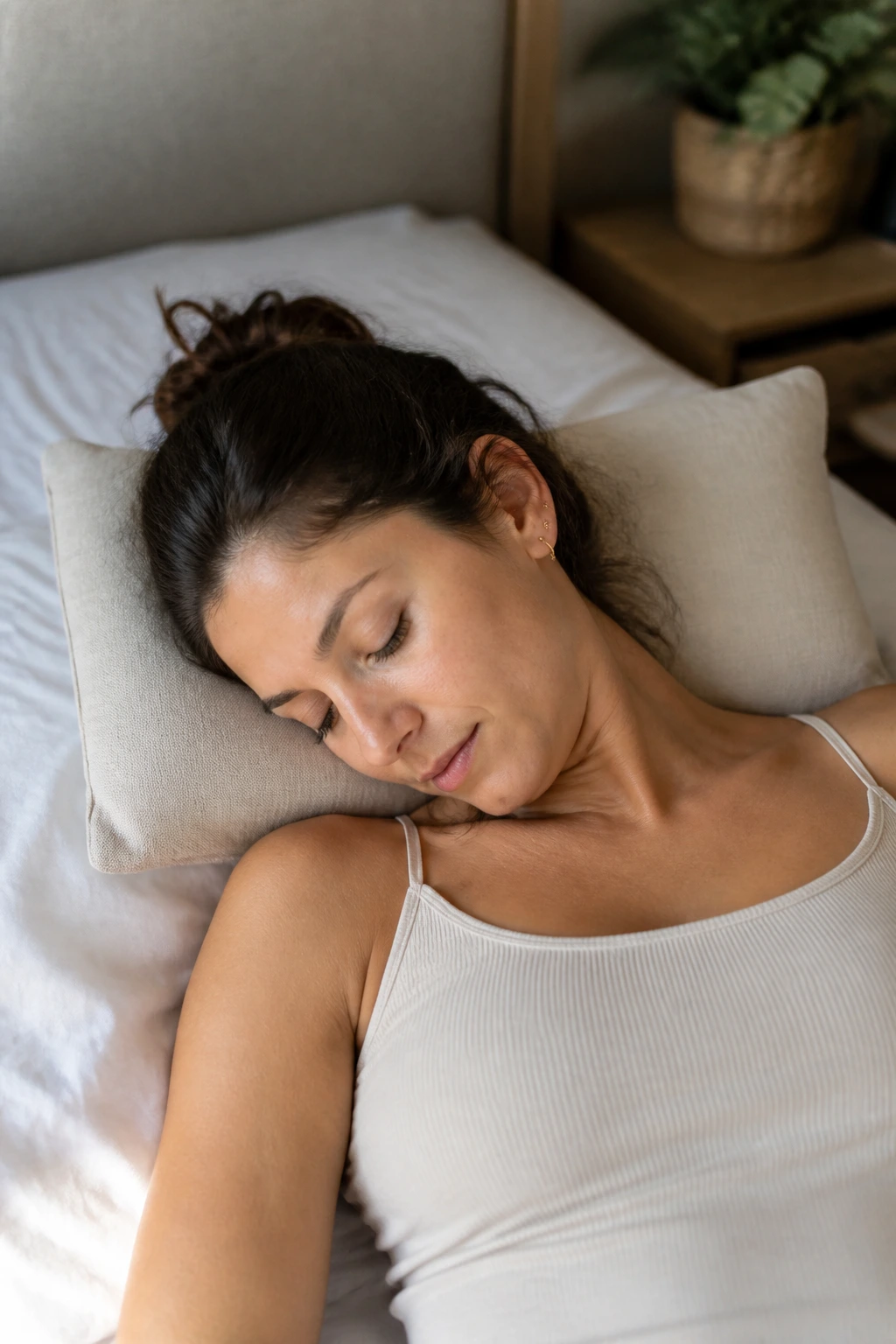 Close-up of a real person on a bed performing gentle neck nods and shoulder releases