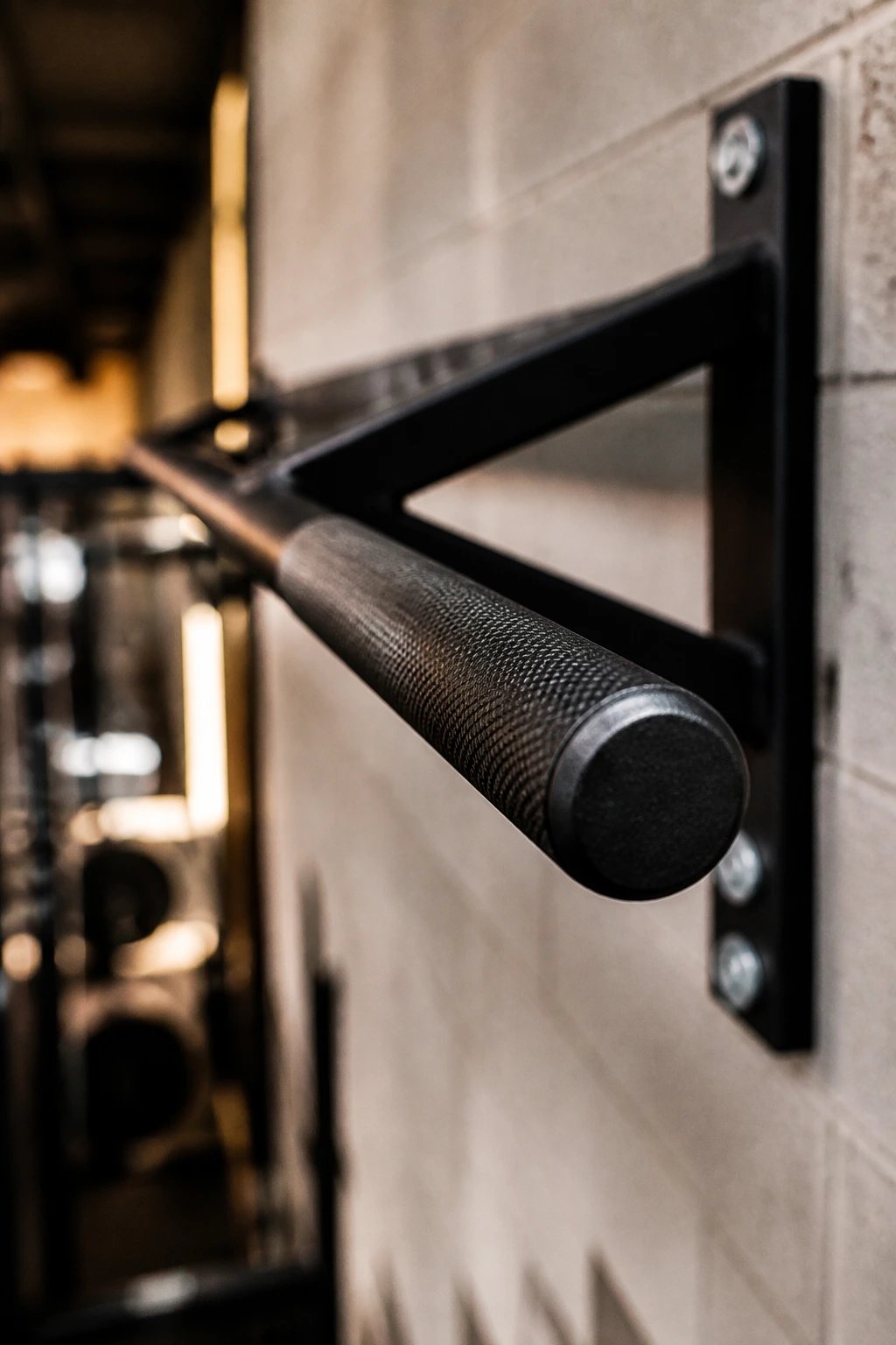 Close-up of the knurled grip on a wall-mounted pull-up bar in a gym