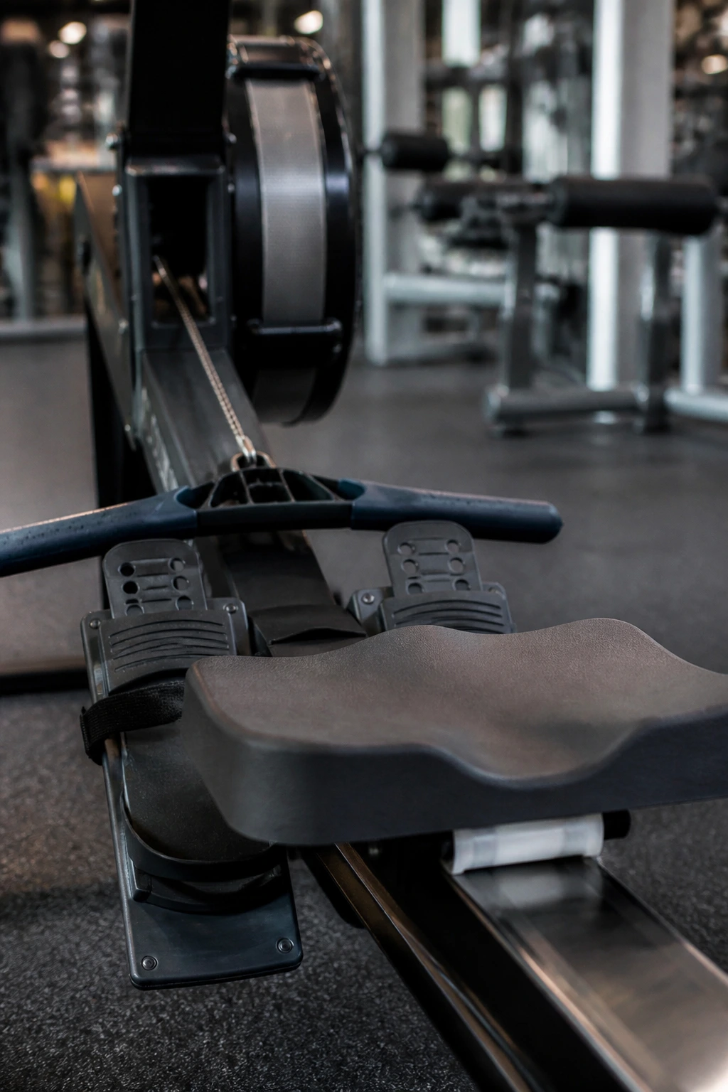 Close-up of a rowing machine handle and seat rail in a gym