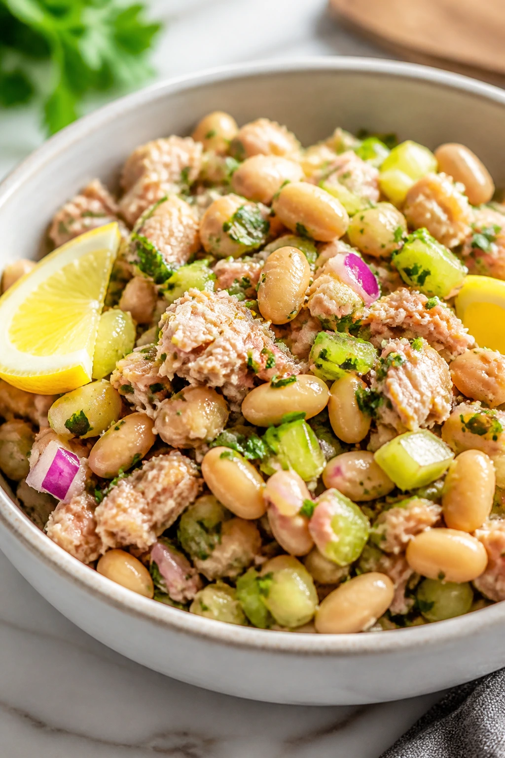 Close-up of tuna and white bean salad on a plate with celery and red onion